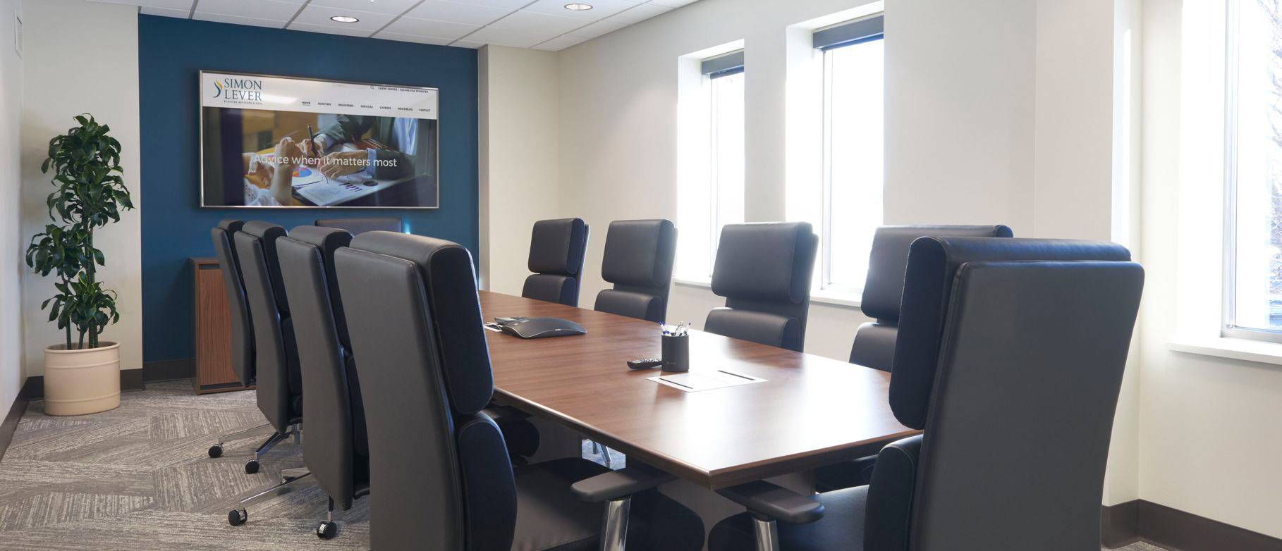 Simon Level conference room after renovation. A square table with 10 chairs and large video display.