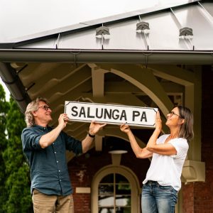 Owners of coffee shop hanging up sign on historic trolley station building